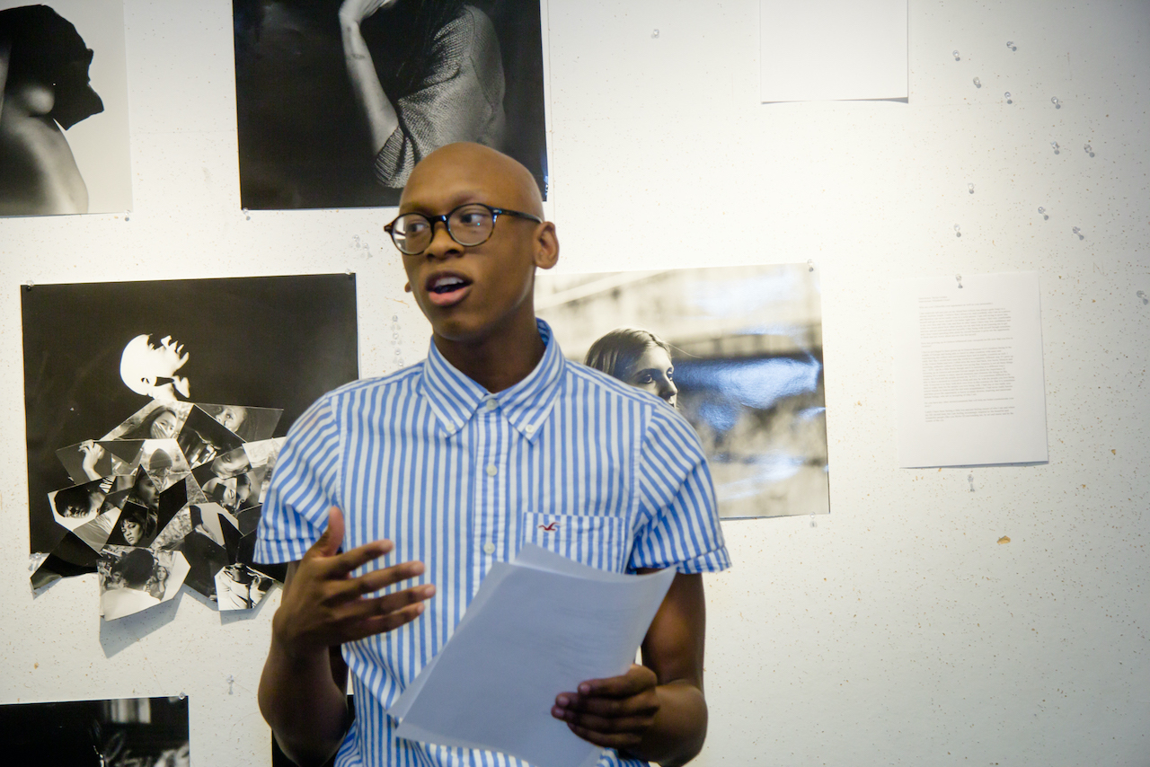 Man standing in an art gallery, holding a script